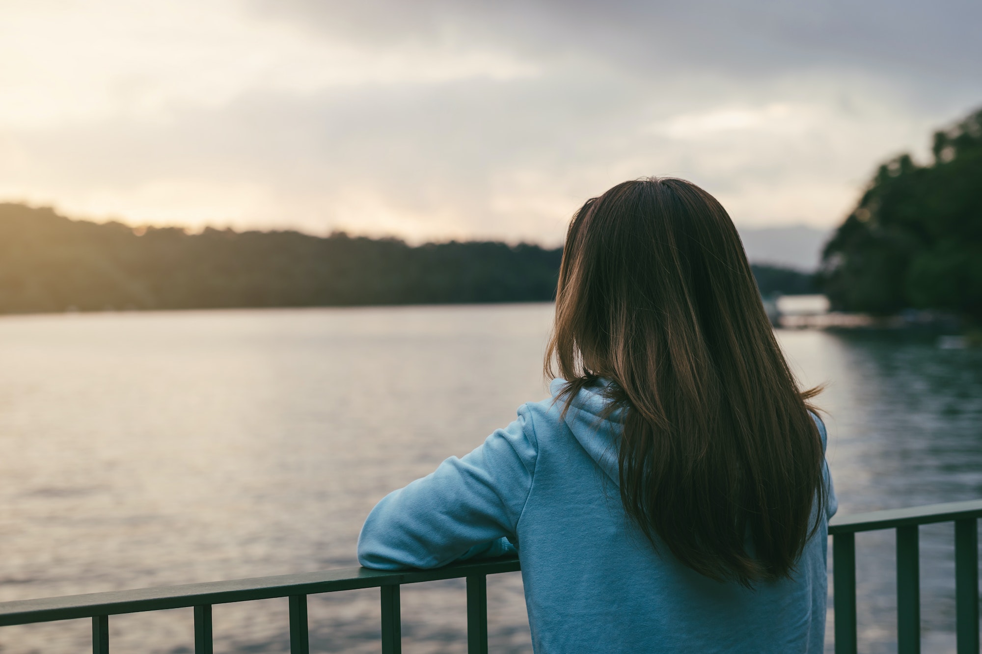 Lonely woman standing absent minded at the river