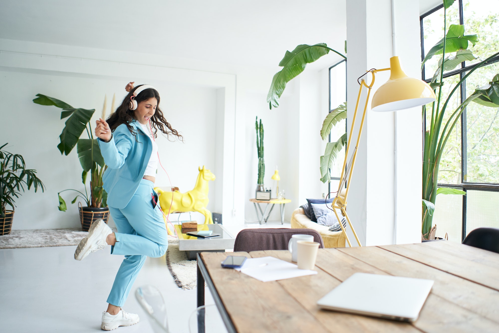 Successful Latina businesswoman dances in office dress celebrating happily at work.